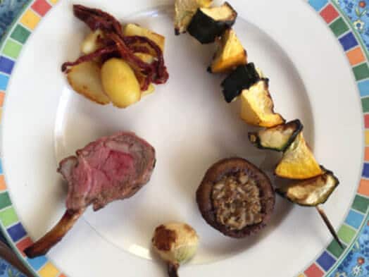 Assiette composée de viande rosée, légumes grillés et champignon farci sur fond coloré