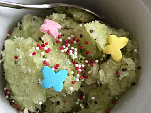 Sorbet de vin blanc décoré de billes colorées et de papillons en sucre dans une coupe avec cuillère