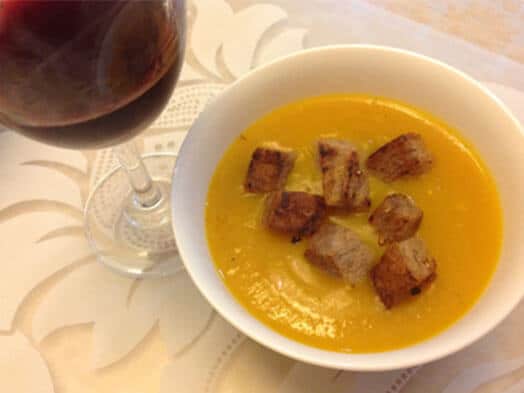 Velouté de courge garni de croûtons grillés accompagné d'un verre de vin rouge