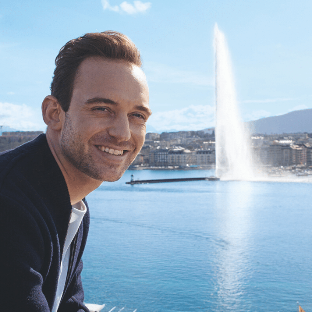 Lächelnder Mann vor dem Genfer Jet d'eau und dem Genfersee
