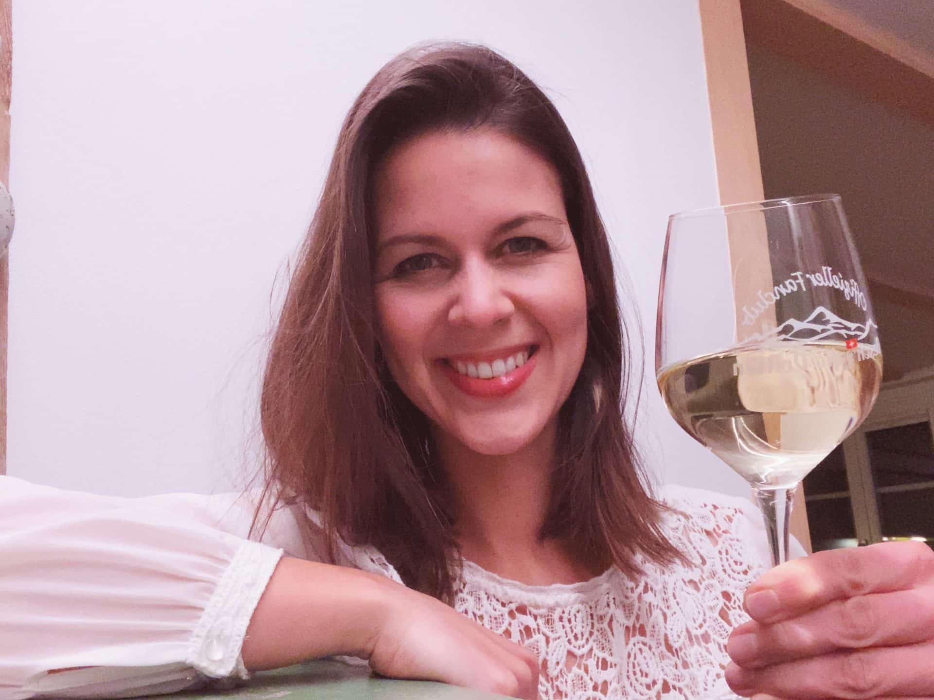 Femme souriante tenant un verre de vin blanc avec logo de montagne gravé