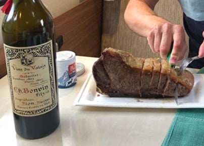 Bouteille de vin Rouvinez accompagnée d'un rôti de viande tranché sur une assiette blanche