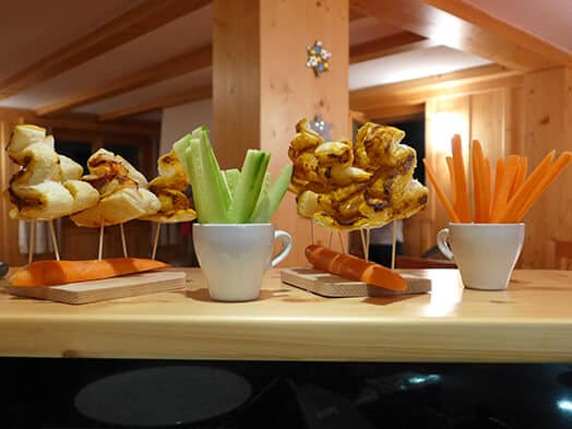 Brochettes apéritives et légumes crus présentés dans des tasses blanches sur un comptoir en bois