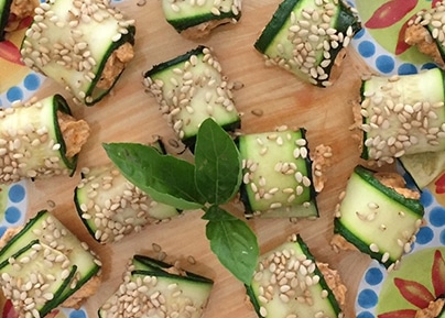 Rouleaux de courgettes grillées garnies de fromage frais et graines de sésame sur une planche en bois